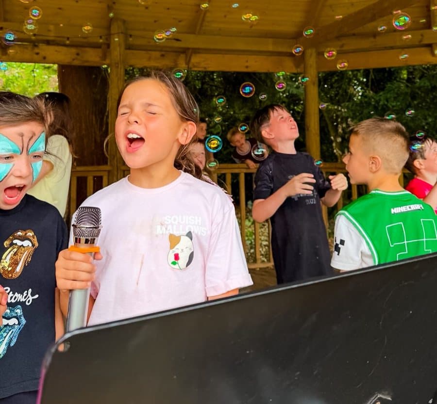 Campers singing into a microphone surrounded by bubbles