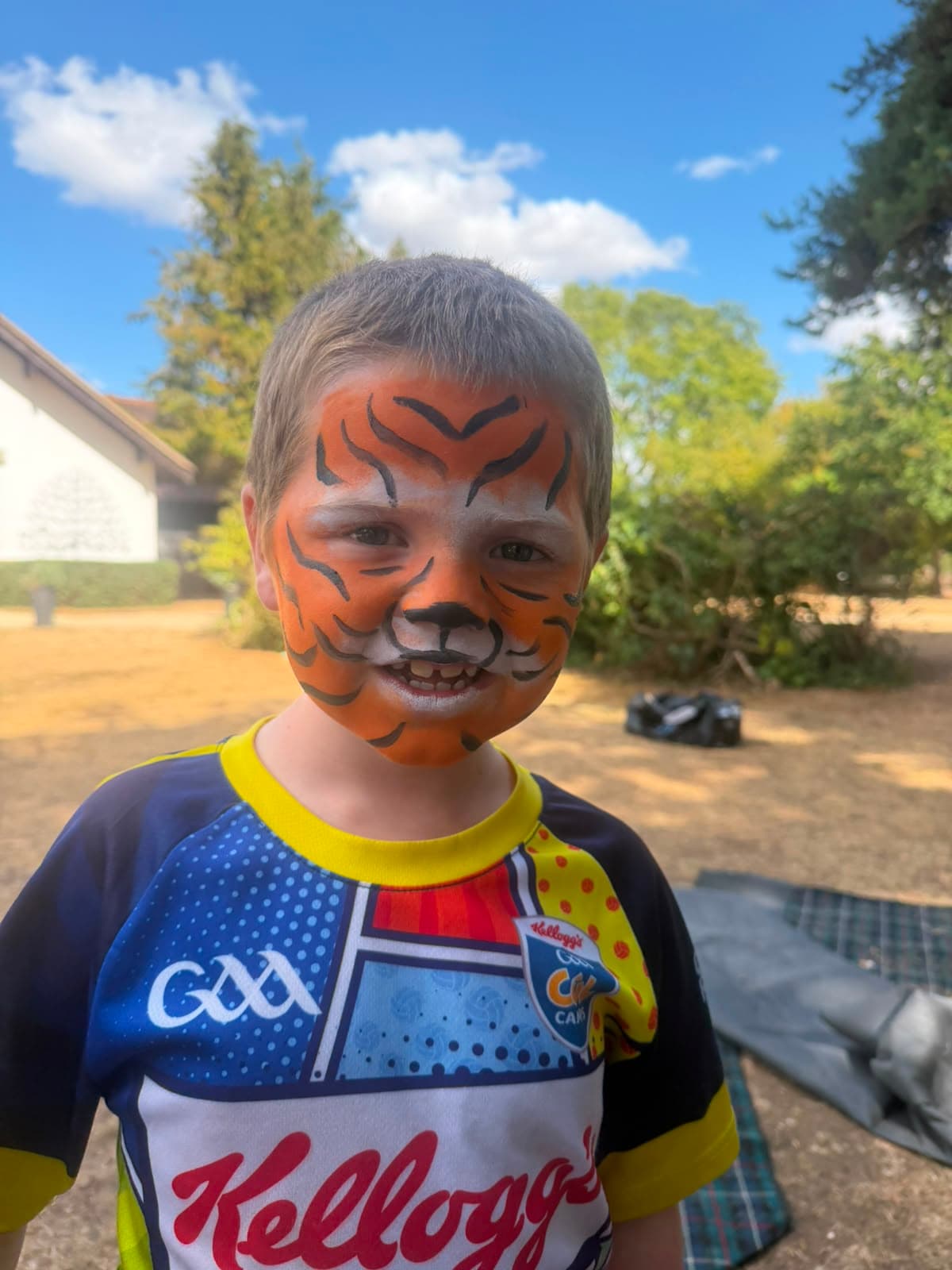 A camper with tiger face paint smiling at the camera