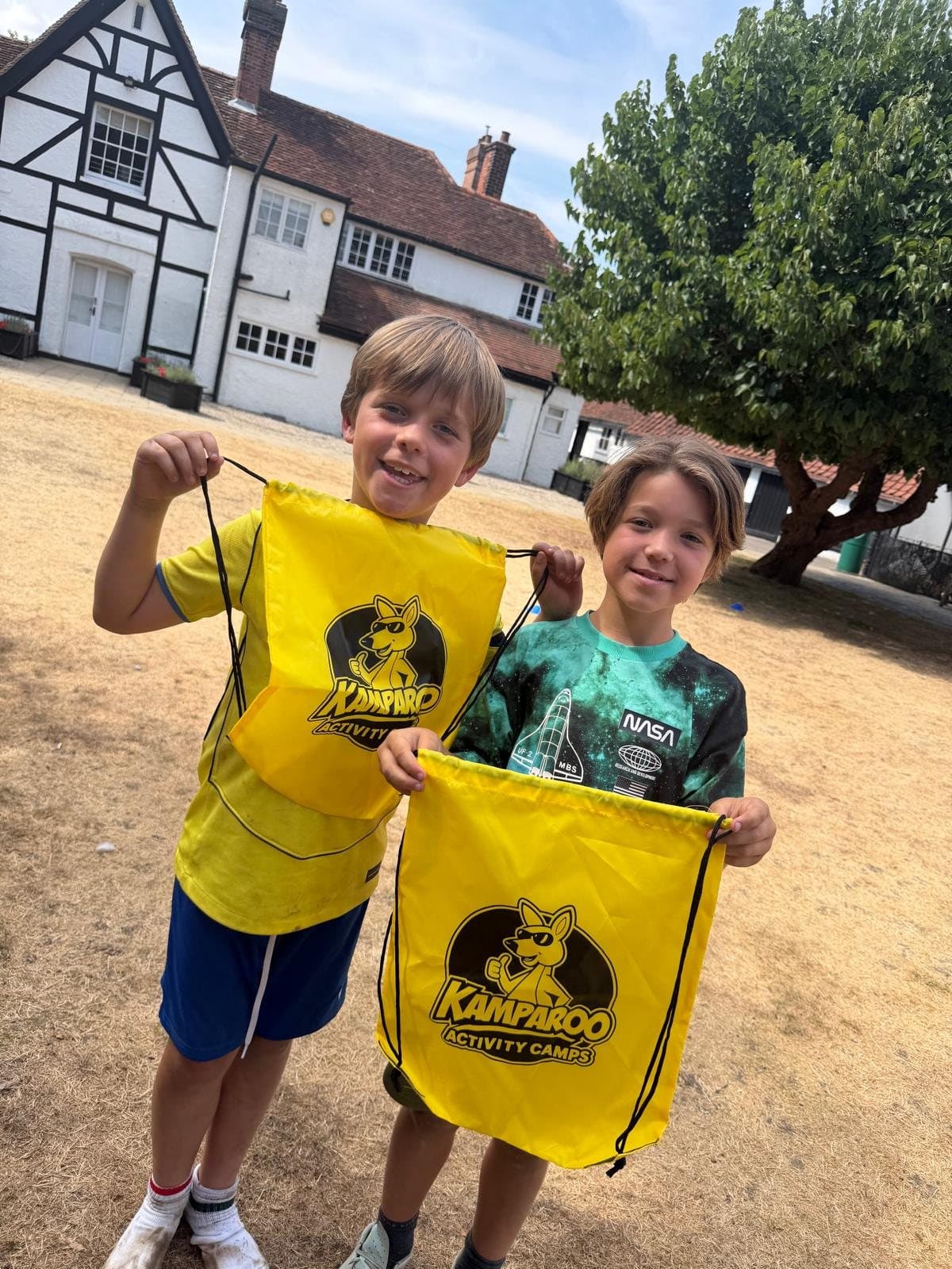 Two Kamparoo campers proudly holding their Kamparoo drawstring bags
