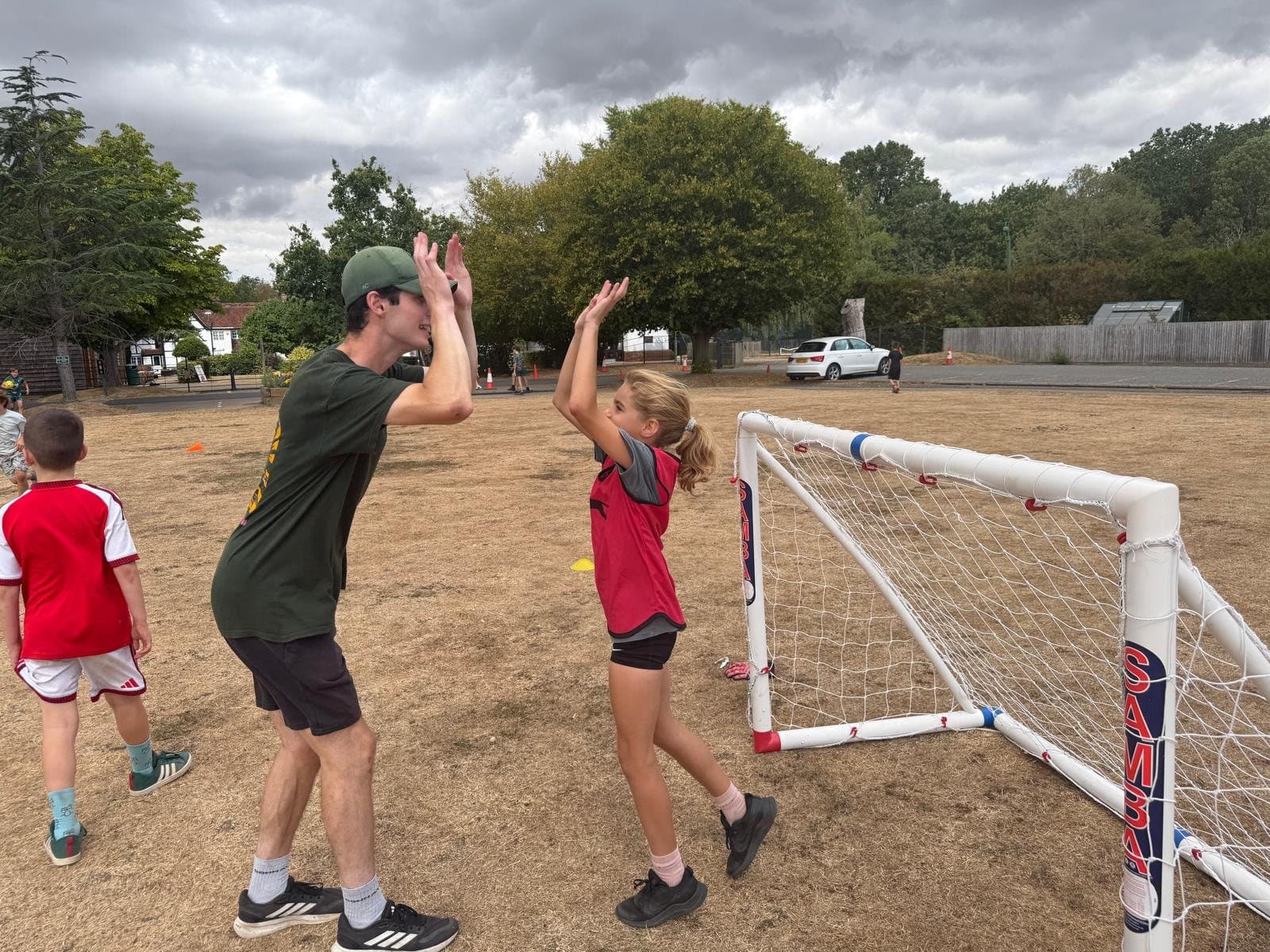 A Kamparoo coach high-fiving a camper during a football session