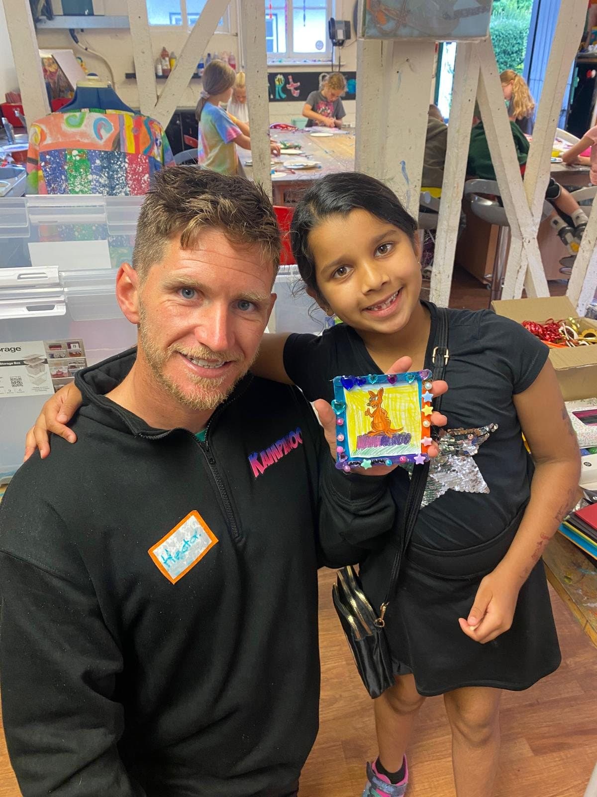 A camper proudly showing a Kamparoo-themed craft she made in an art session