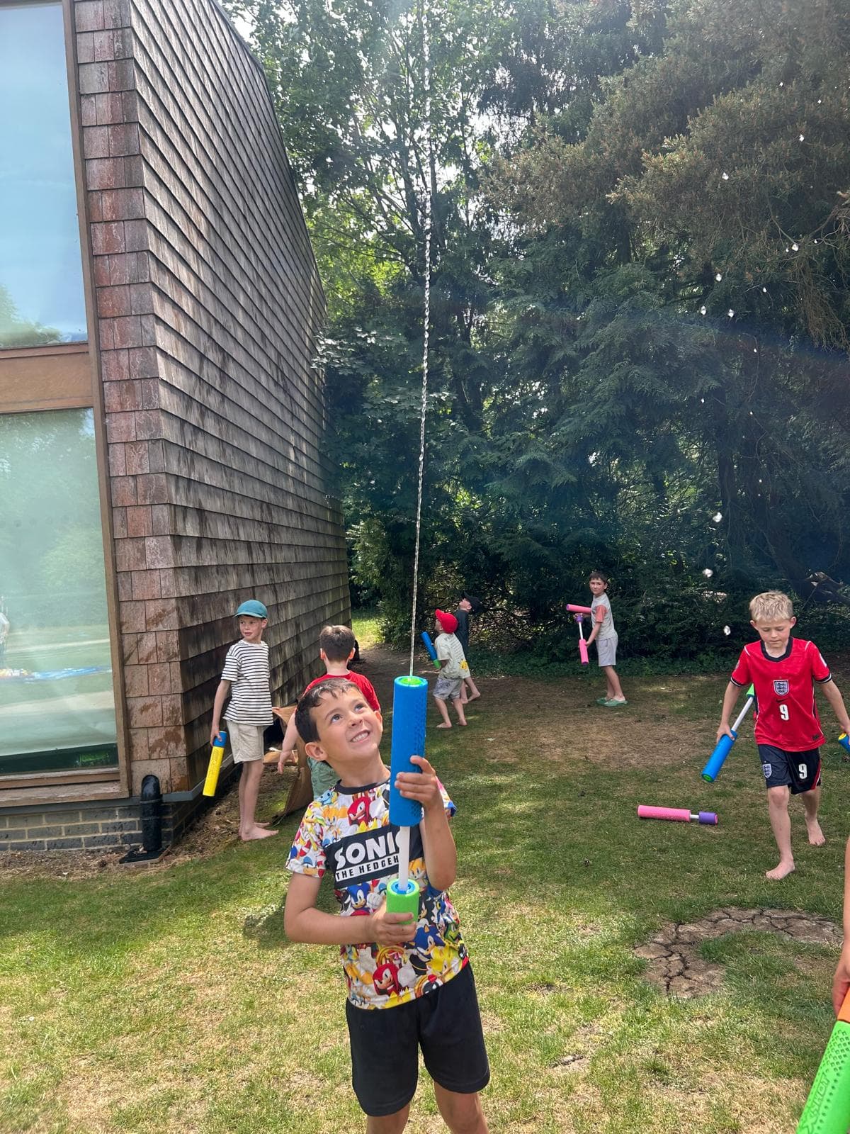 A camper at the front of a water-fight game, squirting a water blaster in the air